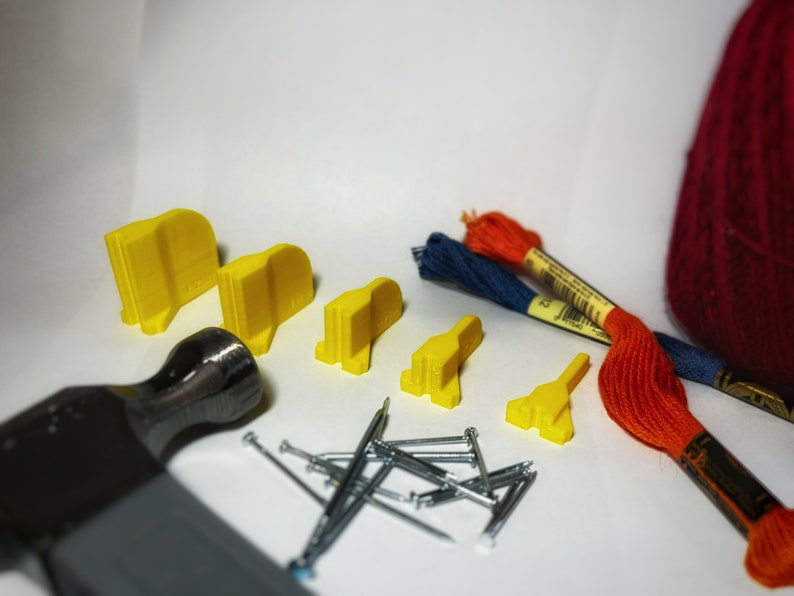 May include: A set of yellow plastic tools for crafting, including a hammer, nails, and small yellow plastic pieces. There are also two spools of embroidery floss, one red and one blue.
