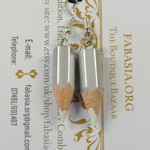 May include: A pair of silver pencil earrings with white eraser tips. The earrings are hanging from silver hooks.