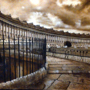 May include: A sepia-toned photograph of a curved row of buildings with a black iron fence in the foreground. The buildings have a classic architectural style with columns and windows. The sky is cloudy and the overall tone is muted.
