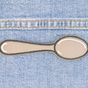 May include: A gray embroidered spoon patch on a blue denim background.