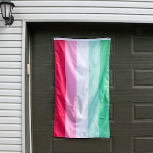 May include: A six-striped pride flag hanging on a garage door. The flag is red, pink, white, light blue, turquoise, and green.