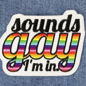 Peut inclure: Patch brodé blanc avec le texte "sounds gay I'm in." Le texte "gay" est en couleurs arc-en-ciel.