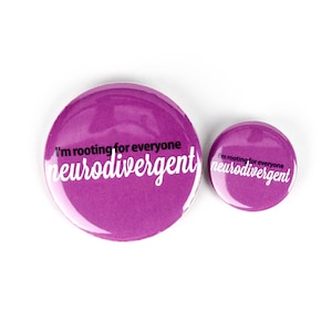 Peut inclure: Deux épingles à bouton violettes avec le texte "I'm rooting for everyone neurodivergent" en lettres blanches.