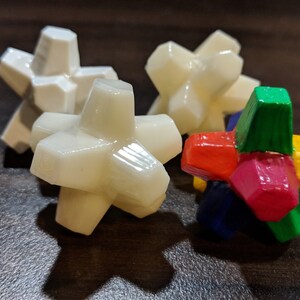 May include: Four star-shaped toys, three are white and one is multi-colored. The multi-colored toy has red, yellow, green, and blue sections.