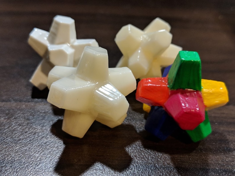 May include: Four star-shaped toys, three are white and one is multi-colored. The multi-colored toy has red, yellow, green, and blue sections.
