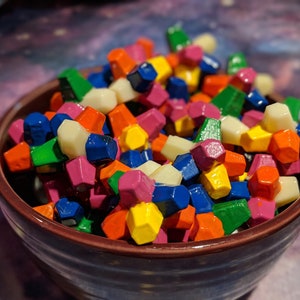 May include: A bowl filled with colorful, geometric shaped candy. The candy is in various shades of red, orange, yellow, green, blue, and white.
