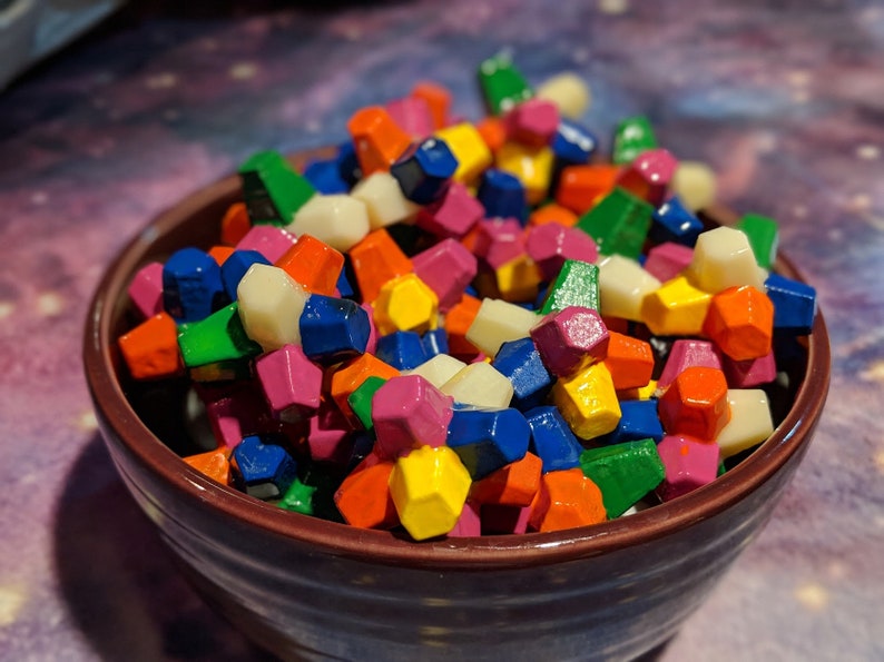May include: A bowl filled with colorful, geometric shaped candy. The candy is in various shades of red, orange, yellow, green, blue, and white.