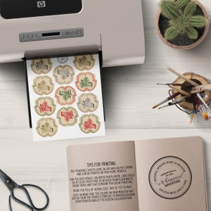 May include: Printable sheets of whimsical Christmas gift tags featuring a reindeer, a tree, and a house with a red roof. The tags are printed on a beige background with a distressed look. The text on the sheet reads "Tips for Printing" and includes instructions for printing the tags. The text on the bottom right corner reads "Original Designs Made in Belgium, Premium Quality, Whimsical Adventure, Created with Love & Care".