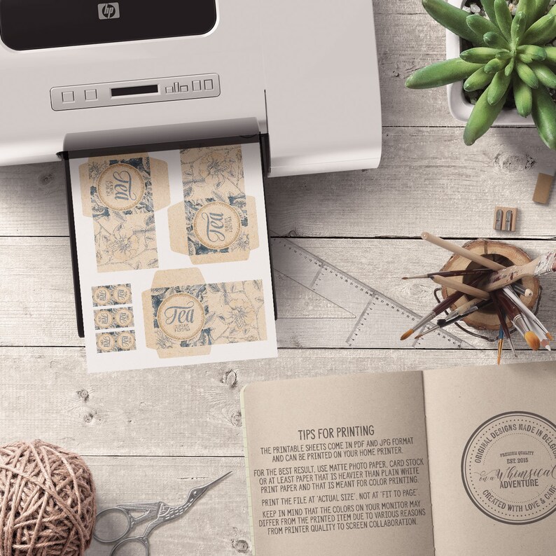 May include: Printable tea box labels with a vintage design. The labels feature a floral pattern with the word "Tea" in a circle. The labels are printed on a light brown paper with a textured surface. The labels are designed to be printed at home.