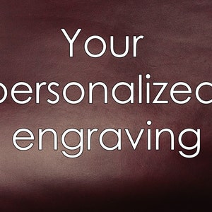 Puede incluir: Primer plano de una superficie de cuero rojo oscuro con el texto "Your personalized engraving" en blanco.