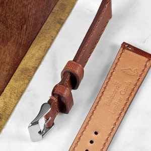 May include: Two brown leather watch straps with stitching detail. One strap has a silver buckle and the other has the text "Dalbanoff Leather Goods" embossed on it.