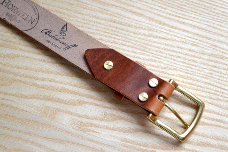 Puede incluir: Un cintur&oacute;n de cuero marr&oacute;n con una hebilla de lat&oacute;n. El cintur&oacute;n tiene una etiqueta de cuero Horween con el texto "Balabanaoff Handcrafted".