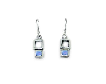 Puede incluir: Un par de pendientes colgantes de plata con una piedra de ópalo azul en cada uno. Los pendientes tienen un diseño cuadrado con un cuadrado más pequeño en el interior.