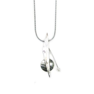 May include: A silver necklace with a pendant featuring a textured circular disc and a long, thin, silver blade. A small pearl hangs from the bottom of the blade.