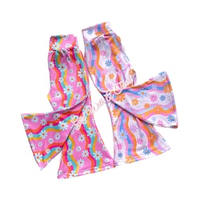 以下が含まれることがあります： 虹とひまわり柄のワイドレッグベルボトムパンツ2本。1本はピンク、もう1本は白です。