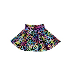 May include: A vibrant, flared skirt featuring a colorful leopard print pattern. The skirt showcases a spectrum of colors, including yellow, blue, purple, and pink, creating a playful and eye-catching design. The skirt is designed for comfort and style.