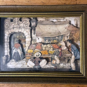May include: A framed illustration of a street scene with a fruit stand. The stand is filled with colorful fruits and vegetables. There are three people in the scene, two women and a man. The women are wearing long dresses and the man is wearing a suit. The illustration is in a brown frame with a gold trim.