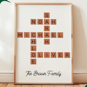 May include: A framed print with a crossword design made from wooden letter tiles. The names Noah, Michael, and Oliver are visible. The text "The Brown Family" is written below. The frame is light brown. The image also includes the text "Custom DIGITAL DOWNLOAD".
