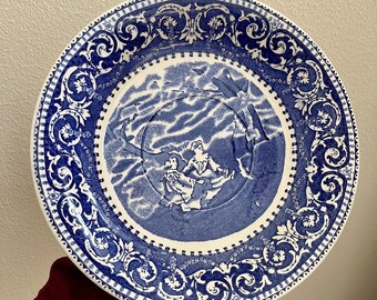 May include: Blue and white ceramic plate with a decorative border and a scene of two figures in a boat on the water.