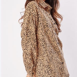 May include: A long-sleeved button-down shirt with a leopard print pattern in shades of brown and black.