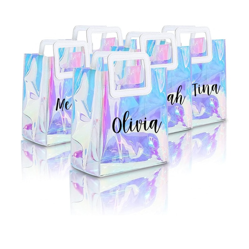 May include: Six iridescent clear plastic tote bags with white handles and black lettering. The bags are personalized with the names "Olivia", "Sarah", "Tina", "Me", and two other names that are not visible.