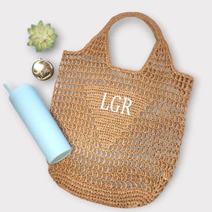 May include: A brown crocheted tote bag with a white monogram that reads "LGR".