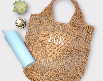 Può includere: Una borsa di tela a rete marrone con un monogramma bianco che dice "LGR".