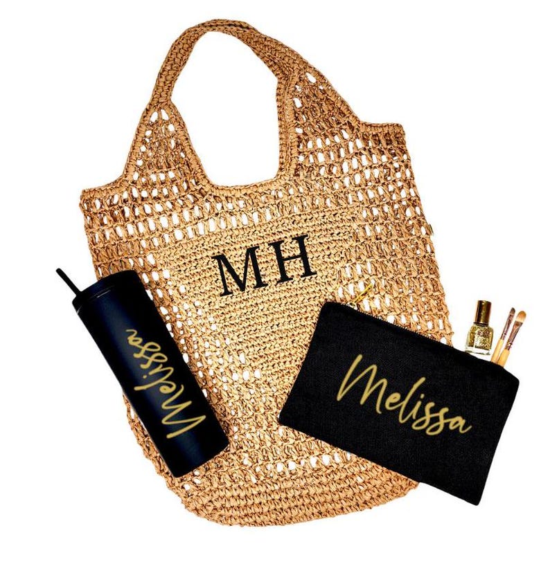 May include: A brown crocheted tote bag with the initials "MH" embroidered on the front. The bag is filled with a black tumbler with the name "Melissa" in gold lettering, a black makeup bag with the name "Melissa" in gold lettering, and a small bottle of nail polish and makeup brushes.