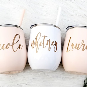 Puede incluir: Tres vasos de vino de acero inoxidable personalizados con letras doradas. Los vasos son rosa, blanco y rosa. Los nombres en los vasos son Nicole, Whitney y Lauren.