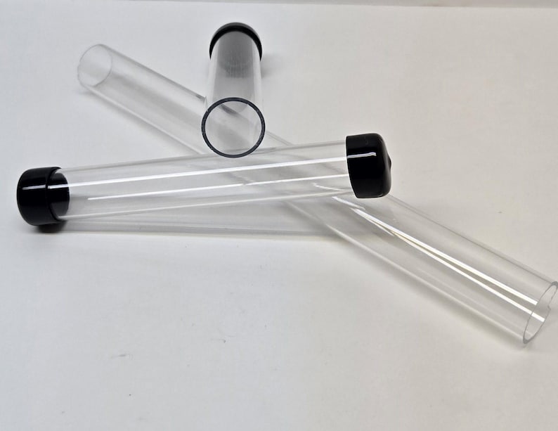 May include: Three clear plastic tubes with black caps. The tubes are lying on a white surface.