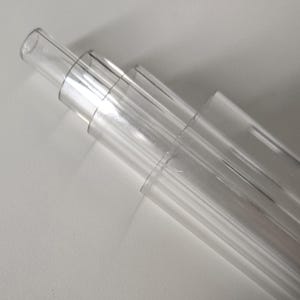 May include: A set of four clear plastic tubes of varying sizes stacked on top of each other.