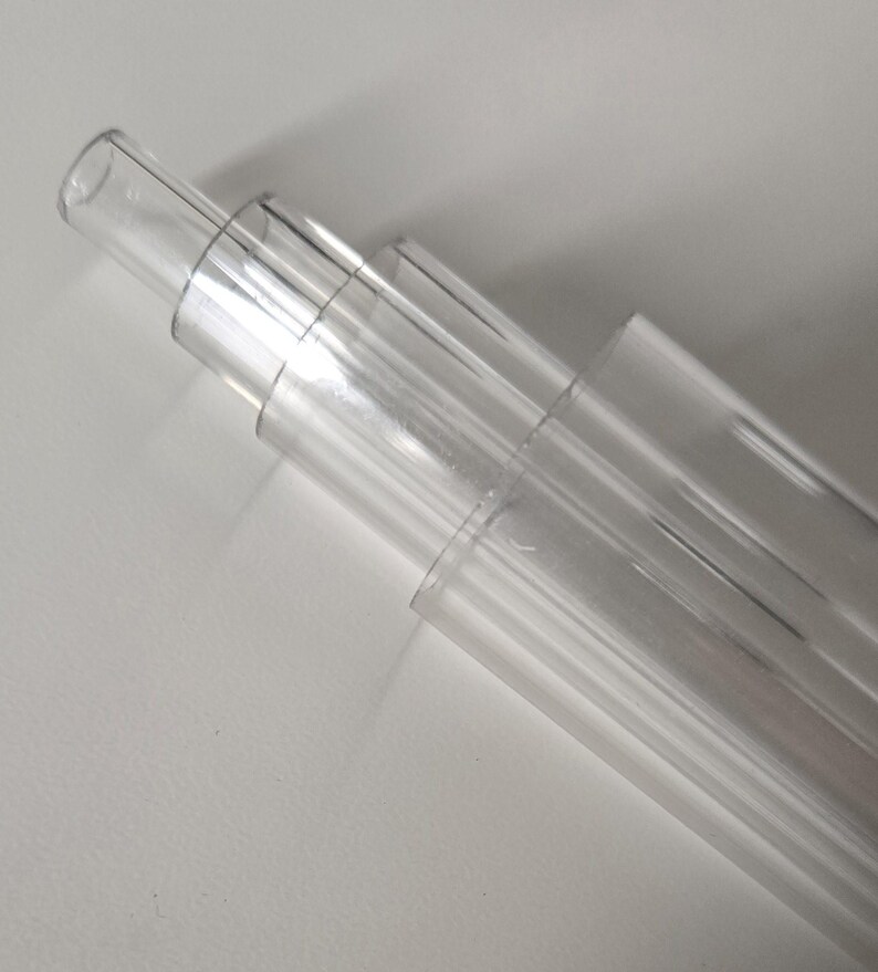May include: A set of four clear plastic tubes of varying sizes stacked on top of each other.