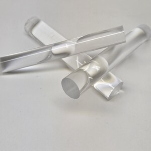 May include: Three clear acrylic rods, each with a rounded end. The rods are arranged in a criss-cross pattern.