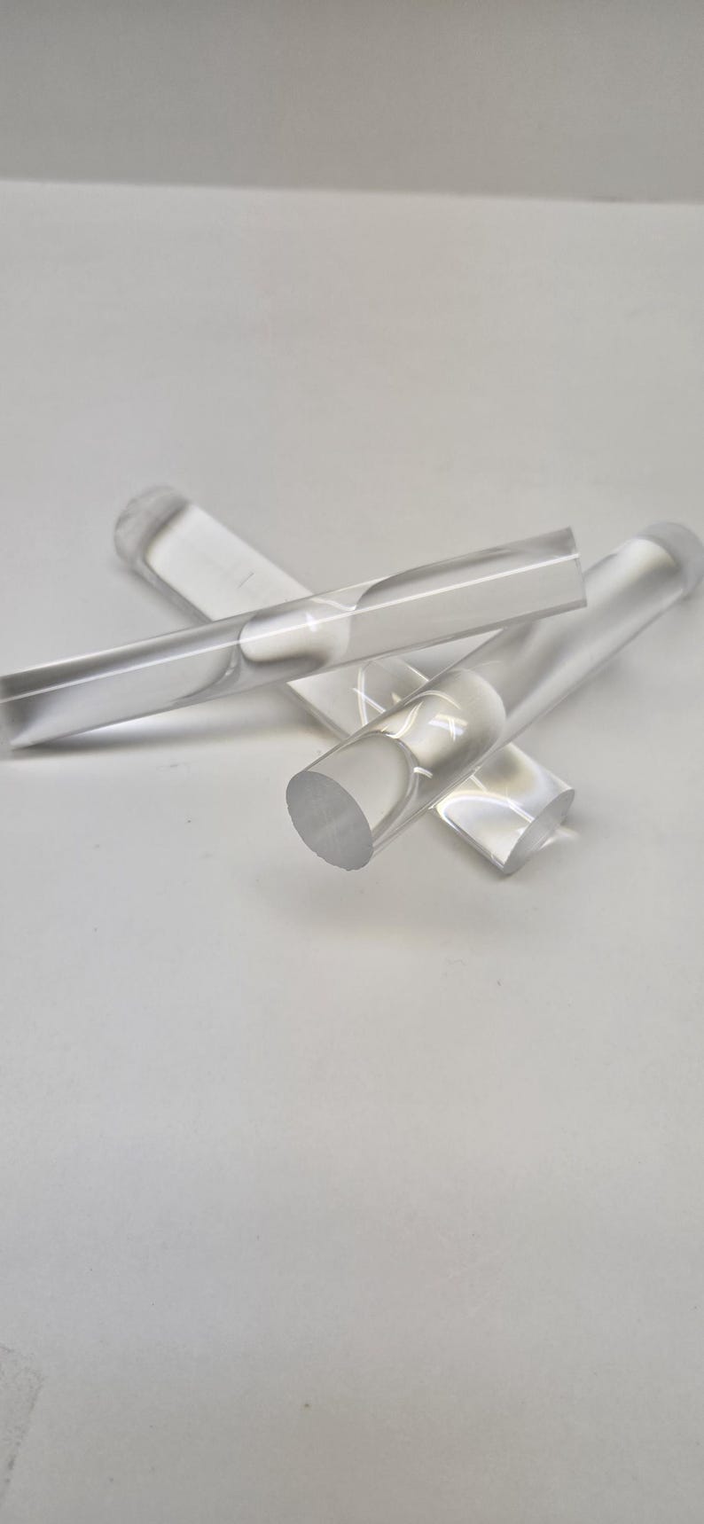 May include: Three clear acrylic rods, each with a rounded end. The rods are arranged in a criss-cross pattern.