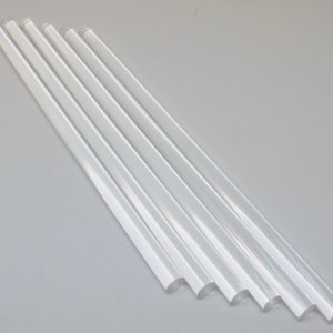May include: Six clear, translucent glue sticks arranged in a diagonal line on a white surface.