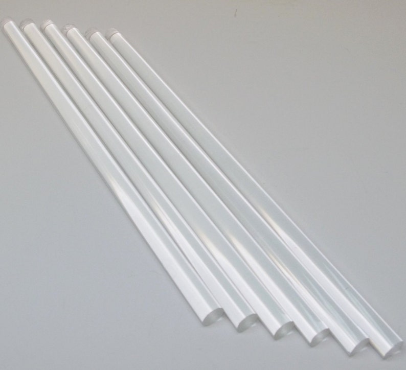 May include: Six clear, translucent glue sticks arranged in a diagonal line on a white surface.