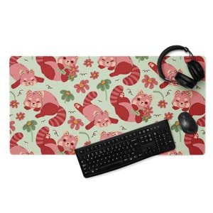 May include: A green and pink mouse mat with a repeating pattern of red pandas and pink flowers. A black keyboard and a black computer mouse are on the mat.