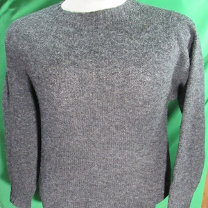May include: A gray sweater with a mock turtleneck collar. The sweater is a solid color and has long sleeves. The collar is white. The sweater is made of a soft, knitted material.
