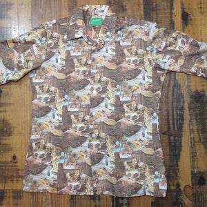 May include: A long-sleeved button-down shirt with a brown and tan pattern. The shirt has a collared neckline and buttoned cuffs. The pattern appears to depict a landscape or architectural design. The shirt is laid flat on a wooden surface.
