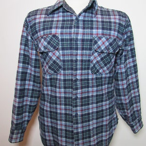 May include: A blue, red, and green checked flannel shirt with two chest pockets and button fastenings. The long-sleeved shirt is displayed on a mannequin, showcasing the classic pattern and design.