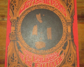 Peut inclure: Affiche de concert vintage avec un fond rouge et une bordure or et noire ornée. L'affiche présente une image centrale d'une personne dans un cercle noir et du texte dans une police stylisée. Le texte comprend "Bill Graham Presents" et "In San Francisco".