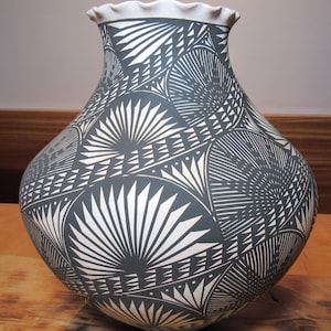 May include: A black and white ceramic pot with a geometric pattern. The pot is decorated with a traditional Southwestern design.