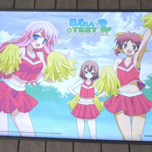 May include: Anime poster featuring three cheerleaders in pink and white uniforms with yellow pom-poms. The poster has the title "Baka & Test: Summon the Beasts" and is set against a blue sky and green background.
