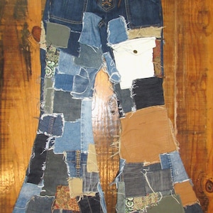 Op de afbeelding: Blauwe denim patchwork jeans met een vetergulp. De jeans heeft een verscheidenheid aan denim patches in verschillende tinten blauw, bruin en andere kleuren. De jeans heeft een uitlopend pijp ontwerp en zakken.