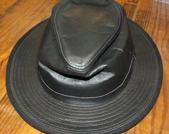 May include: A black leather fedora hat with a wide brim and a soft, foldable crown.