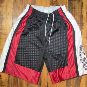 May include: Black mesh basketball shorts with red and white side panels and the Adidas logo on the right leg.