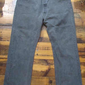 Puede incluir: Un par de pantalones vaqueros de color gris oscuro con cierre de botón y cinco bolsillos.