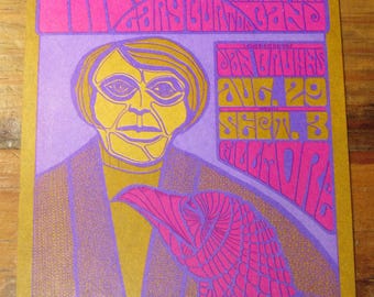 Peut inclure: Affiche de concert vintage aux tons or, violet et rose. L'affiche présente un texte stylisé et une illustration d'une personne avec une figure d'oiseau. Le texte comprend le nom du groupe, le lieu et les dates.