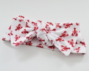 May include: White headband with a red lobster print. The headband is tied in a bow.