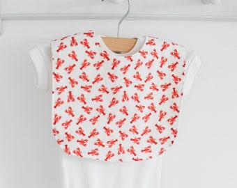 May include: White baby bib with a red lobster print.